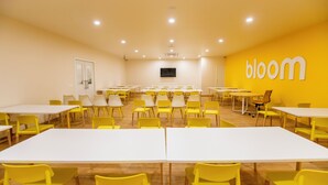A conference room with yellow chairs and white tables, a large screen, and a 'bloom' sign on the wall. - Bloom Hub - Guindy (Chennai)
