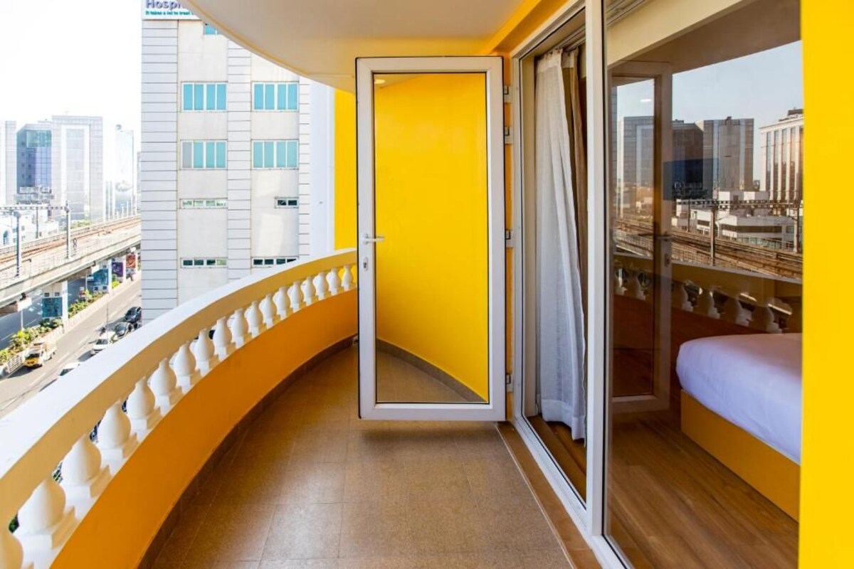 A hotel room with a balcony, a bed, a window, and a door.