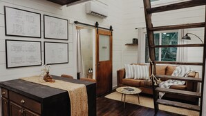 Un salon chaleureux avec une table en bois foncé, un canapé marron et une grande fenêtre.
