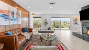 Una sala de estar moderna con un sofá de cuero, una mesa de centro de vidrio y una chimenea.