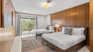 Un dormitorio moderno con dos camas, un ventanal grande y una lámpara en el techo.