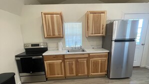 Una cocina con armarios de madera, un refrigerador de acero inoxidable, una estufa y un fregadero.