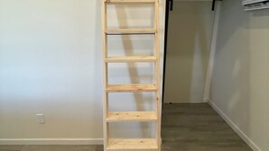 Una escalera de madera en una habitación con pared blanca y una lámpara en el techo.