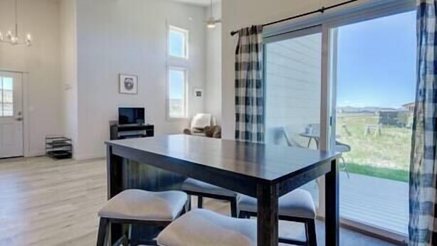 Una sala moderna con una gran mesa de comedor, dos sillas, un televisor y vistas al exterior.