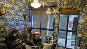 A room with patterned wallpaper, a glass table, and a chair with a cushion. - Banaras Rest House  (Varanasi)
