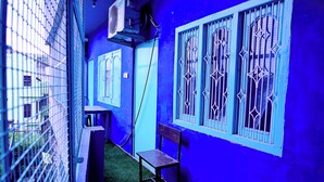A narrow corridor with a blue wall, a metal gate, and a bench. - Banaras Rest House  (Varanasi)