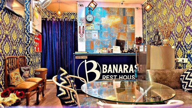 A reception area with a blue curtain, a reception desk, and a glass coffee table. - Banaras Rest House  (Varanasi)