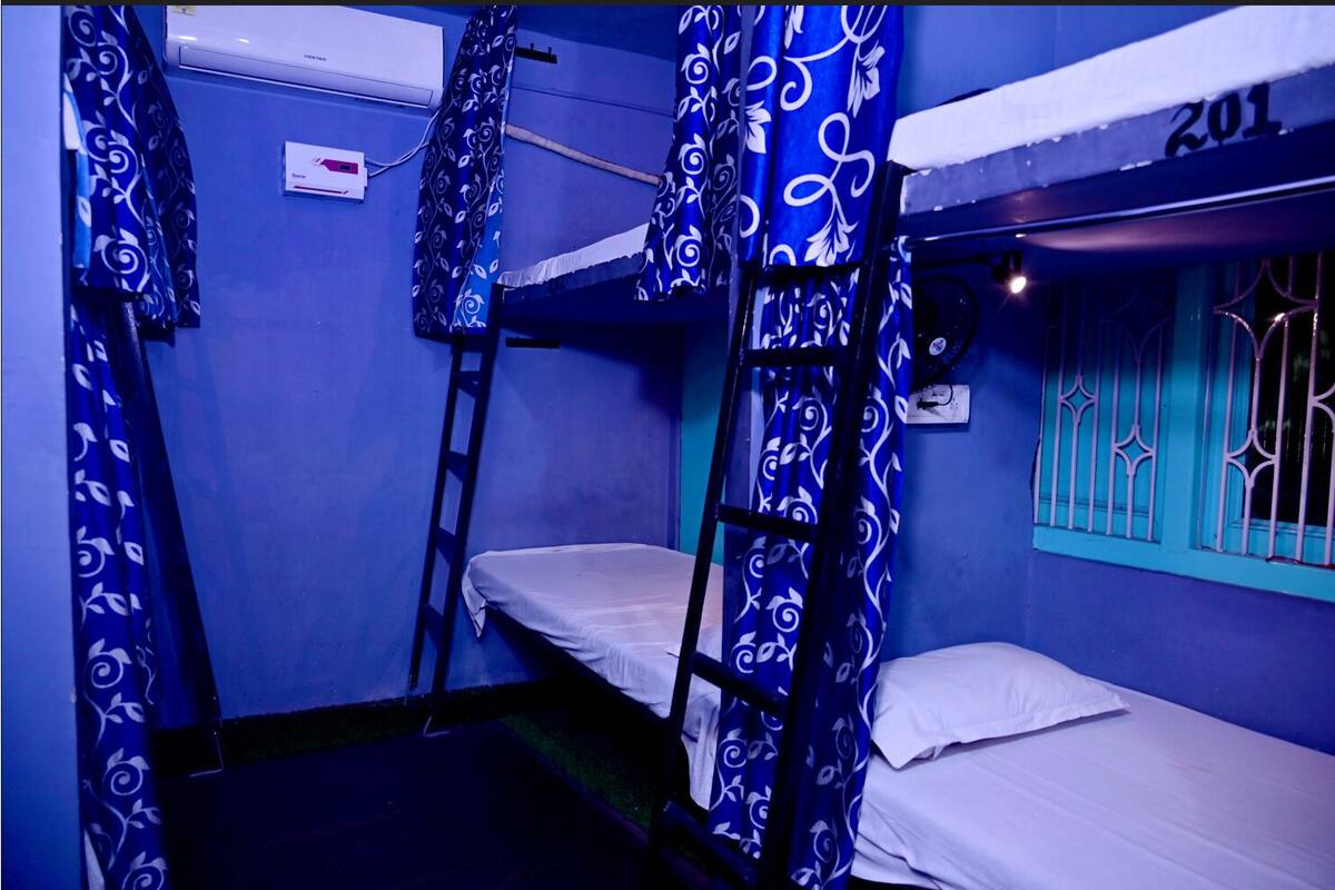 Une chambre de dortoir avec des lits superposés, une échelle et des rideaux à motifs.