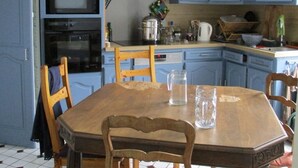 Une cuisine avec des meubles de rangement bleus, une table à manger en bois et un sol carrelé.