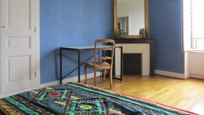 Une chambre à coucher avec un lit, une chaise, un miroir et une cheminée.