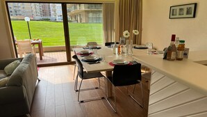 Ein moderner Essbereich mit großem Fenster, einem gedeckten Esstisch mit Tellern und Gläsern sowie einer Couch im Vordergrund.