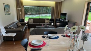 Ein modernes Wohnzimmer mit einer Couch, einem Esstisch und einem Fernseher.