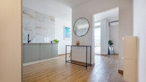 Een ruime keuken met een marmeren achterwand, een ronde spiegel en een houten vloer.