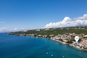 A coastal town with a clear blue sea, boats, and a mix of residential buildings. - Beachfront Santa Maria 2 Apartment 1 (Novalja)