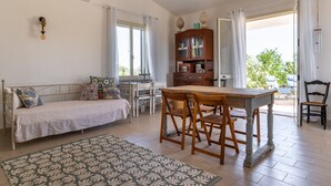 A room with a bed, a dining table with chairs, a cabinet, and a window with curtains. - Villetta al Plemmirio by Wonderful Italy (Syracuse)