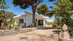 A modern house with a paved driveway, surrounded by various plants and trees. - Villetta al Plemmirio by Wonderful Italy (Syracuse)