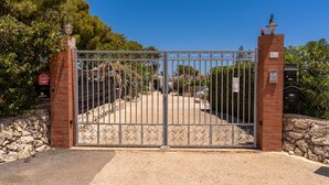 A gated entrance with a brick wall and metal gate. - Villetta al Plemmirio by Wonderful Italy (Syracuse)