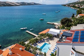 Un hotel frente al mar con piscina, tumbonas y vistas al océano.