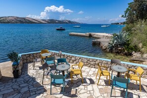 Un patio de piedra con mobiliario exterior que da a una masa de agua con barcos.