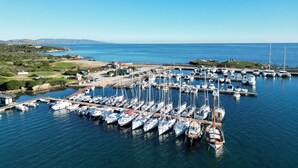 Un puerto deportivo con numerosas embarcaciones amarradas, rodeado de un paisaje costero.