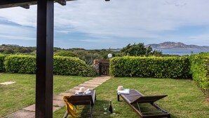Un espacio de estar techado al aire libre con vista al mar y las montañas.