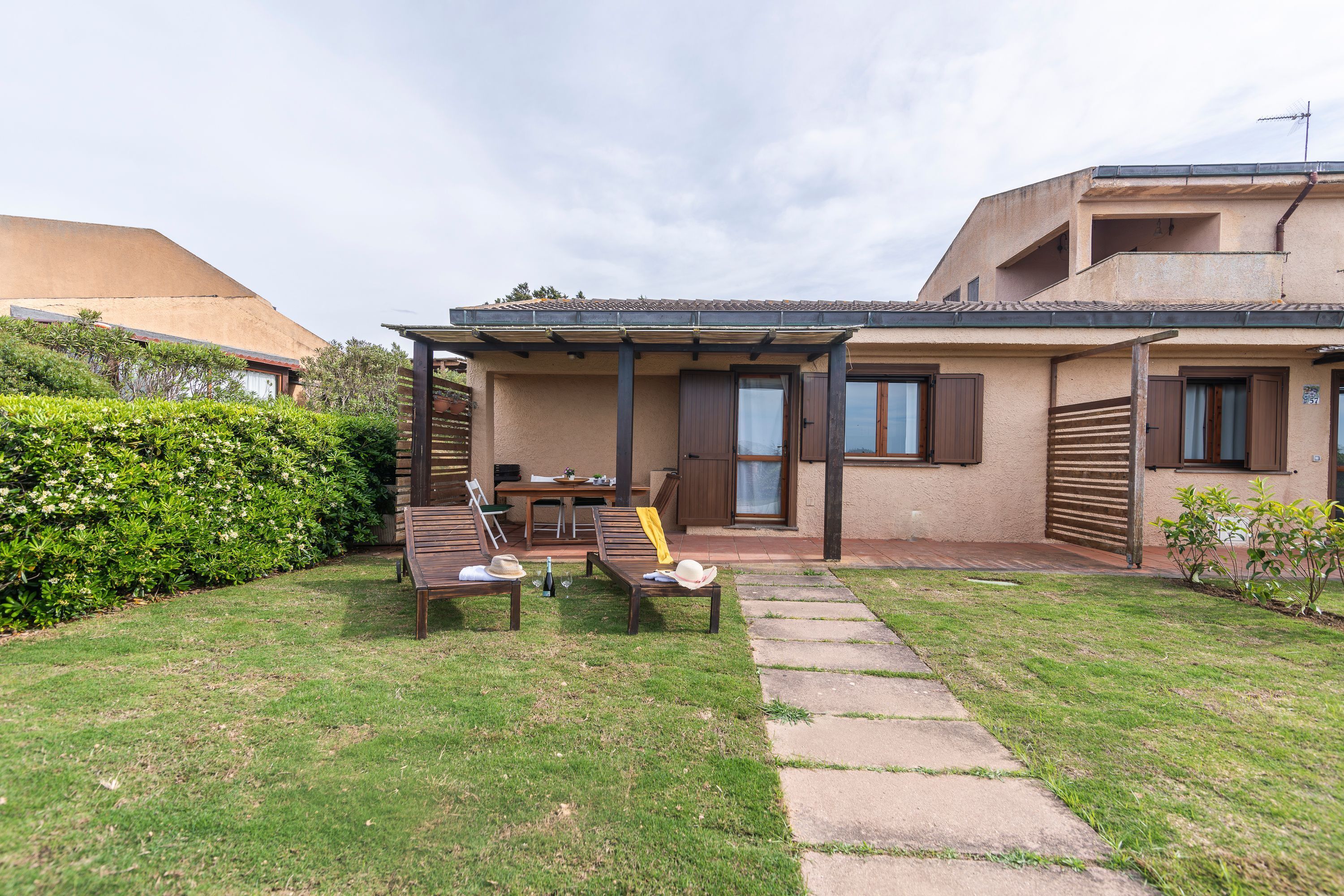 A house with a patio area featuring two wooden chairs, a table, and a yellow umbrella.