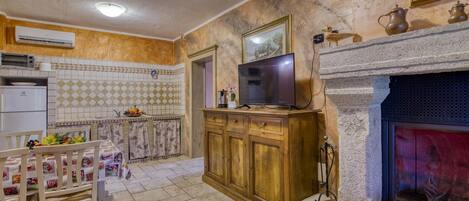 A kitchen with a tiled backsplash, a wooden cabinet, a television, and a fireplace.