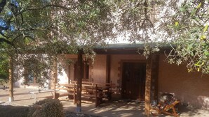 An outdoor seating area with wooden benches and tables, a stone wall, and a door leading to a building. - Appartamento Uva Shared Pool (Roccastrada)