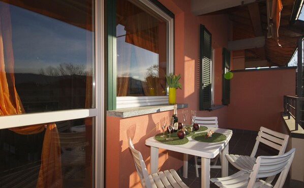 A dining area with a table set for two, a bottle of champagne, and a vase with flowers. - Casa Fiorita Pool and Lake (Leggiuno)
