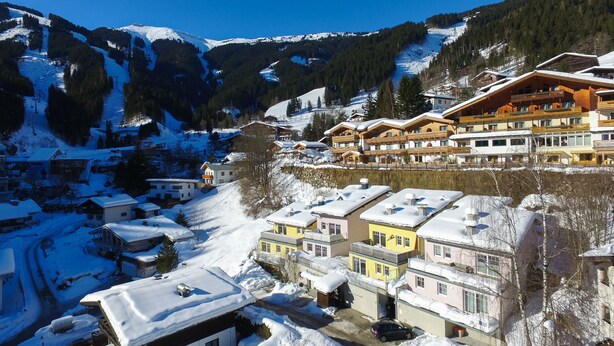 A snow-covered village with traditional wooden buildings, a ski slope in the background, and a clear blue sky. - Penthouse Summer Winter Fun 4 Roof Terrace (Zell am See)