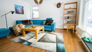 A modern living room with a blue sofa, a wooden coffee table, and a bookshelf. - Penthouse Summer Winter Fun 4 Roof Terrace (Zell am See)