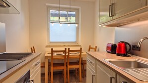 A compact kitchen with a dining table, chairs, a toaster, a kettle, and a sink. - Penthouse Summer Winter Fun 4 Roof Terrace (Zell am See)