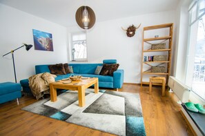 Un salon moderne avec un canapé bleu, une table basse en bois et une bibliothèque.
