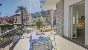 A balcony with a table set for dining, a stone wall, and a view of the neighborhood. - Il Giardino Di Dante Stresa Center (Stresa)