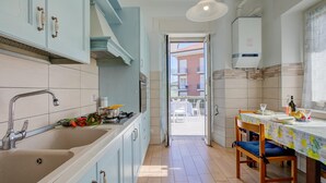 A kitchen with a sink, stove, and dining area with chairs and table. - Il Giardino Di Dante Stresa Center (Stresa)