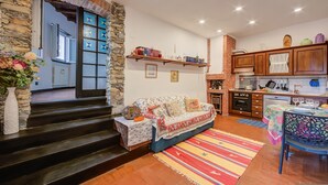 Ein gemütliches Wohnzimmer mit einer Couch, einem Couchtisch und einem Teppich. Es gibt eine Küchenzeile mit Holzschränken und einem Esstisch.