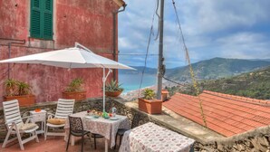 Eine Terrasse im Freien mit Tisch, Stühlen und Topfpflanzen.