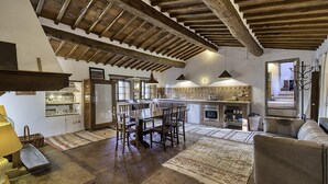 A spacious living area with a dining table, sofas, and a kitchen in the background. - Casale Al Sole Tra Le Vecchie Vigne 6 (Radda in Chianti)
