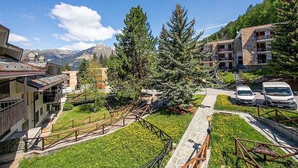 Resort com vista para as montanhas, estacionamento e um caminho que leva aos edifícios.