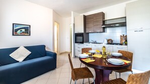 Une cuisine moderne avec des meubles blancs, une table à manger dressée avec des assiettes, des couverts et une bouteille.