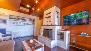 Een moderne woonkamer met een open haard, een aan de muur bevestigde televisie en een boekenkast vol boeken.