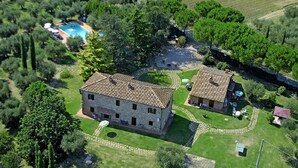 An aerial view of a property with two stone buildings, a swimming pool, and surrounding greenery. - Cornflower apt With Shared Pool (Castiglione del Lago)
