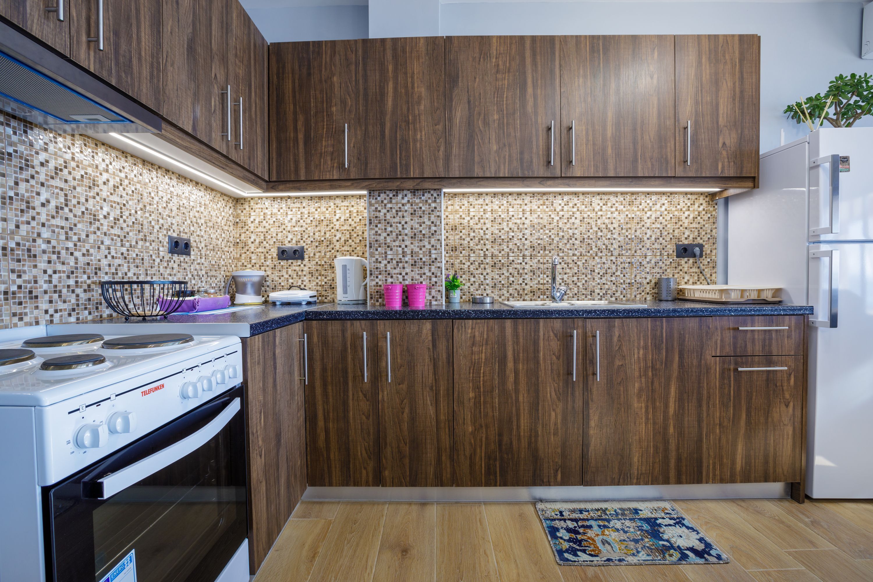 A modern kitchen with wooden cabinets, a gas stove, and a tiled backsplash.