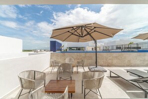 Terraza en la azotea con piscina, mobiliario exterior y vistas despejadas del horizonte urbano.