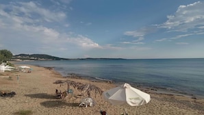 Una spiaggia con ombrelloni, sedie e vista sul mare.