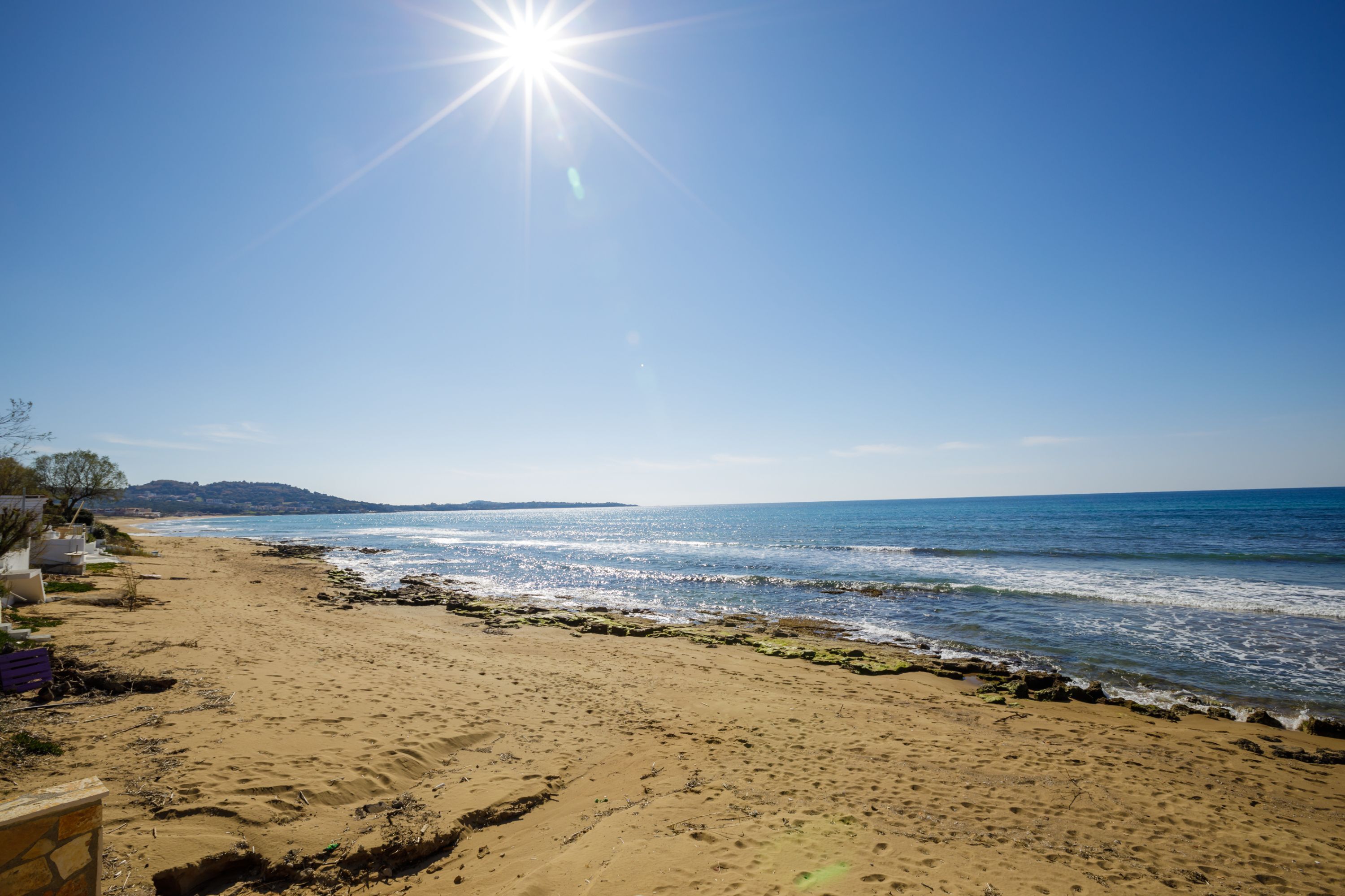 A beach with clear skies, a sandy shore, and a view of the sea.