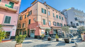 A street with buildings, outdoor seating, and a dog on a leash. - Goccia Di Mare Appartment (Alassio)