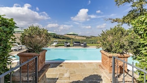 A swimming pool with stone steps leading up to it, surrounded by greenery and a clear sky. - Maramaldo Sangiovese Shared Pool Chianti (Castelfiorentino)