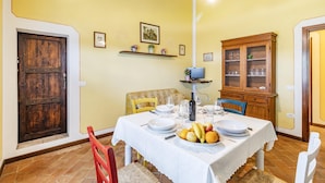 A dining area with a table set for four, a wooden cabinet, and a door. - Maramaldo Sangiovese Shared Pool Chianti (Castelfiorentino)