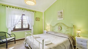 A bedroom with a bed, a nightstand, a chair, and a window with curtains. - Maramaldo Sangiovese Shared Pool Chianti (Castelfiorentino)
